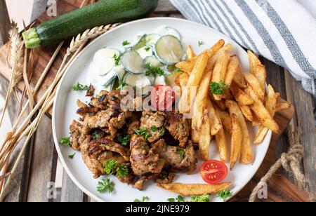 Maiale fritto con patatine fritte fatte in casa e insalata di zucchine su un piatto Foto Stock