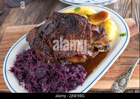 Arrosto di festa con gambo di tacchino arrosto, cavolo rosso, patate e sugo Foto Stock