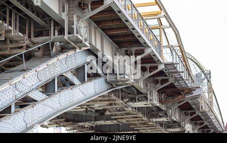 Pali di metallo ponte coperto pedonale con molti rivetti. Potente struttura a ponte in ferro, vista da sotto rivetti di ferro di grandi dimensioni. Un fiume scorre sotto il br Foto Stock