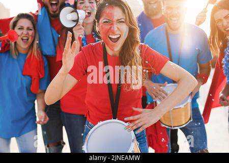 Gli appassionati di sport pazzi suonano la batteria e gridano mentre sostengono la loro squadra - Focus on center girl drum Foto Stock