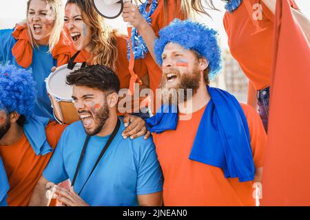 Tifosi pazzi che urlano mentre sostengono la loro squadra - Focus sul volto del ragazzo sinistro Foto Stock