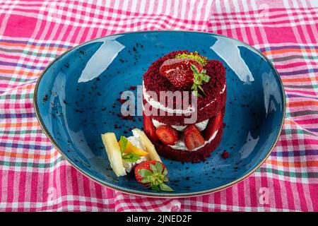 Torta dolce singola. Torta al cioccolato glassata, un pezzo, su piatto nero con torta di fragole. Viene servito su un piatto di fragole. Foto Stock