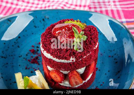 Torta dolce singola. Torta al cioccolato glassata, un pezzo, su piatto nero con torta di fragole. Viene servito su un piatto di fragole. Foto Stock