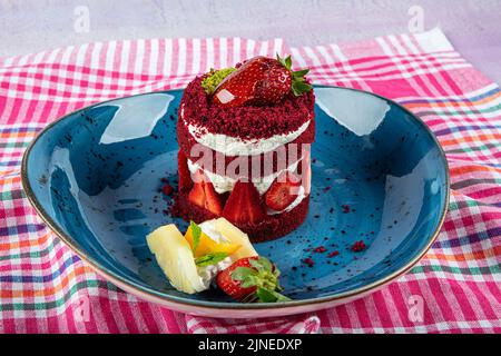 Torta dolce singola. Torta al cioccolato glassata, un pezzo, su piatto nero con torta di fragole. Viene servito su un piatto di fragole. Foto Stock