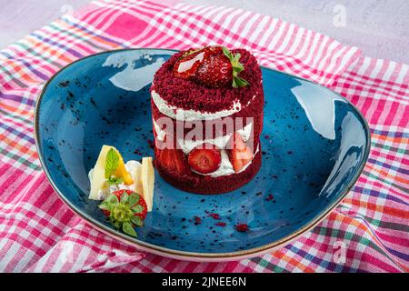 Torta dolce singola. Torta al cioccolato glassata, un pezzo, su piatto nero con torta di fragole. Viene servito su un piatto di fragole. Foto Stock