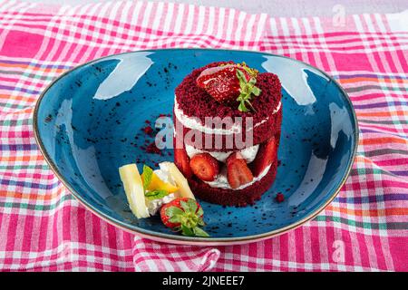 Torta dolce singola. Torta al cioccolato glassata, un pezzo, su piatto nero con torta di fragole. Viene servito su un piatto di fragole. Foto Stock