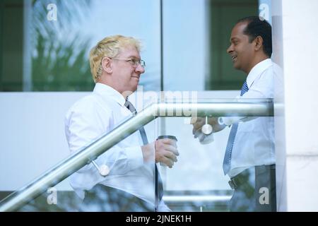 Allegri uomini d'affari multietnici che parlano e bevono caffè Foto Stock