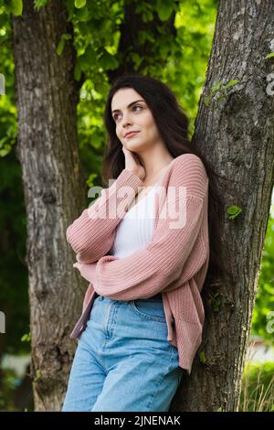 bruna donna in maglia cardigan guardando lontano in parco, immagine stock Foto Stock