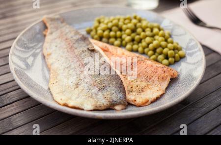 Appetitosi filetti di trote al forno con piselli verdi Foto Stock