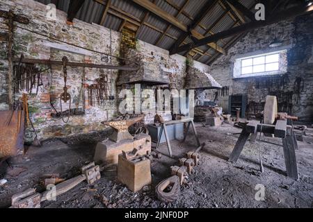 Un'incudine arrugginita nel mezzo dell'area sporca e vecchia del negozio di fabbro. Al Big Pit National Coal Museum di Pontypool, Galles, Regno Unito. Foto Stock