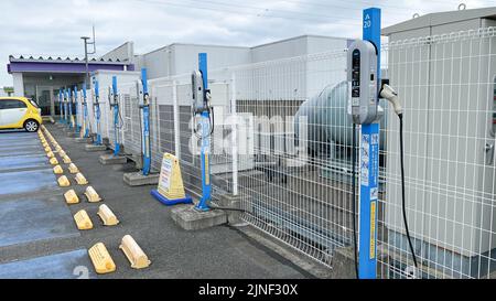 Una fila di caricabatterie per veicoli elettrici standard NEC Corp. In cima a un parcheggio sul tetto presso un centro commerciale EON con una sola ricarica per auto presso uno degli stans Foto Stock