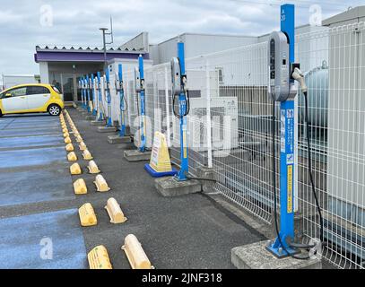 Una fila di caricabatterie per veicoli elettrici standard NEC Corp. In cima a un parcheggio sul tetto presso un centro commerciale EON con una sola ricarica per auto presso uno degli stans Foto Stock