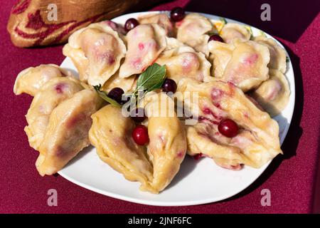 Gnocchi, ripieni di ciliegie, bacche. Pierogi, varenyky, vareniki pirohy - gnocchi con ripieno piatto popolare Foto Stock