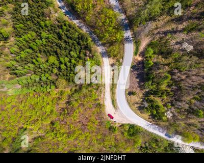 Vista aerea dall'alto verso il basso del drone della strada curva nella foresta. Foto Stock