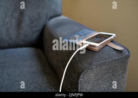cellulare ricarica su braccio di sedia all'interno casa hertfordshire inghilterra Foto Stock