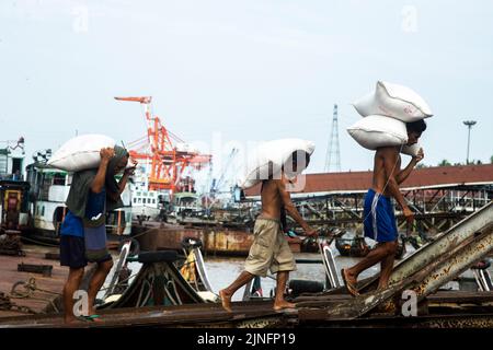 Yangon, Myanmar. 11th ago, 2022. Gli operai trasportano le borse di riso ad un molo in Yangon, Myanmar, il 11 agosto 2022. I proventi delle esportazioni agricole del Myanmar sono diminuiti del 1,25 per cento a circa 1,27 miliardi di dollari USA su base annuale nei primi quattro mesi dell'attuale anno fiscale (FY) 2022-2023, secondo il Ministero del Commercio. Il paese del sud-est asiatico ha cambiato il proprio anno fiscale dall'ottobre-settembre originale ad aprile-marzo a partire da quest'anno. Credit: MYO Kyaw Soe/Xinhua/Alamy Live News Foto Stock