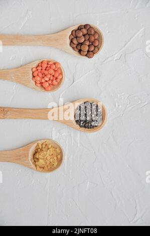 Diversi o vari tipi di fagioli secchi o legumi secchi in cucchiaio di legno su fondo bianco. Grani interi, alimento sano e concetto di dieta. Vista dall'alto. F Foto Stock