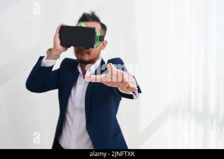 Un uomo d'affari in un visore vr che stretching la mano per toccare qualcosa Foto Stock