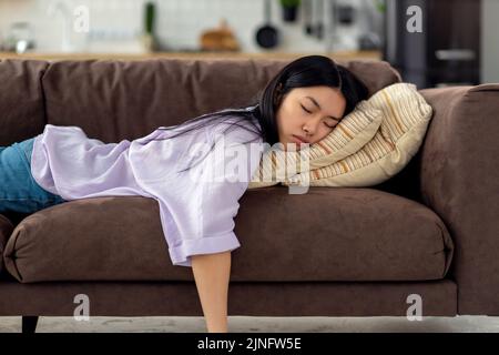 Una giovane donna caucasica stanca si addormenta sul divano dopo un duro concetto di fatica della giornata lavorativa Foto Stock
