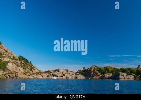 scogliera rocciosa vicino all'acqua di mare blu con cielo blu sopra Foto Stock