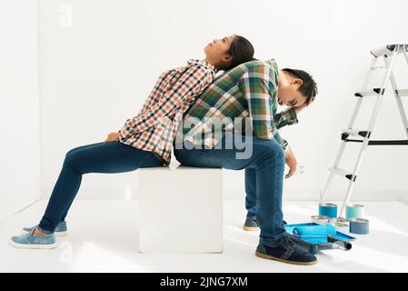Una giovane coppia stanca che si siede al piano dopo la ristrutturazione della camera Foto Stock