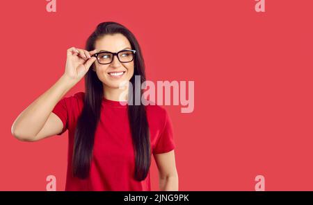 Ritratto di felice donna millenaria in occhiali classici con cornice nera su sfondo rosso. Foto Stock
