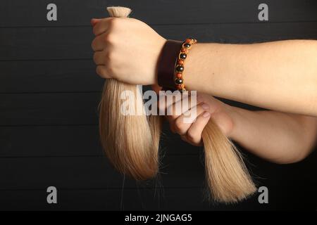 La mano maschio tiene le sezioni di capelli per l'estensione. Foto Stock