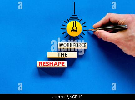 Modificare la forma del simbolo della forza lavoro e del supporto. Concetto parole ridisegnare la forza lavoro su blocchi di legno. Mano uomo d'affari. Splendido sfondo blu. Business Foto Stock