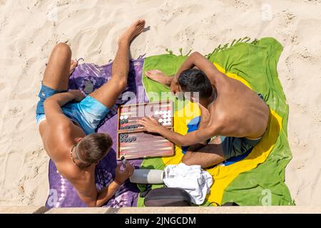 Uomini che giocano a backgammon sulla spiaggia di Tel Aviv. Tel Aviv, situata lungo la costa mediterranea, è il fulcro culturale di Israele e una delle principali destinazioni di viaggio che attrae turisti da tutto il mondo. Foto Stock