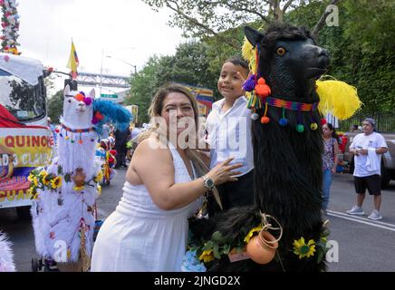 Un venditore e suo figlio in uno stand con una statua di animali in legno. Alla parata ecuadoriana NYC 2022 a Jackson Heights, Queens, New York City. Foto Stock