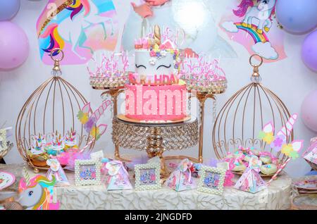 Festa di compleanno della bambina; tavolo da dessert con una bella torta di unicorno, dolci, biscotti allo zucchero e decorazione di compleanno Foto Stock