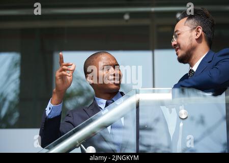 Allegri colleghi multietnici di successo che parlano all'aperto insieme Foto Stock