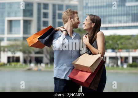 Una bella giovane coppia che si diverti a trascorrere del tempo insieme all'aperto dopo aver fatto shopping Foto Stock