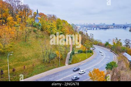 Il traffico su Volodymyrsky Descent Road, che conduce al lungofiume del fiume Dnieper a St Volodymyr Hill, coperto di parco autunnale, Kyiv, Ucraina Foto Stock