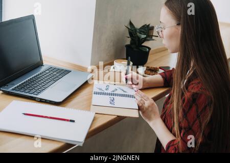 Principali obiettivi di vita, come stabilire e realizzare gli obiettivi di vita. Ragazza giovane donna che scrive negli obiettivi di vita del taccuino Foto Stock