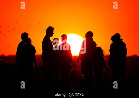 Una folla di persone guarda il sole tramontare da una collina a Ealing, Londra occidentale. L'Ufficio MET ha emesso un avvertimento color ambra per il calore estremo che copre quattro giorni da giovedì a domenica per parti dell'Inghilterra e del Galles come nuovi telai ad onda di calore. Data immagine: Giovedì 11 agosto 2022. Foto Stock