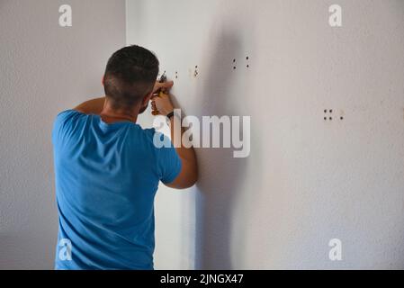 Carpentiere rimuovendo le viti dalla parete. Lavorare a casa. Foto Stock