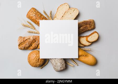 Minimal carta bianco mockup su sfondo di tipi di pane fatto in casa. Diversi tipi di pane fresco come sfondo, vista dall'alto con spazio per il tuo tex Foto Stock