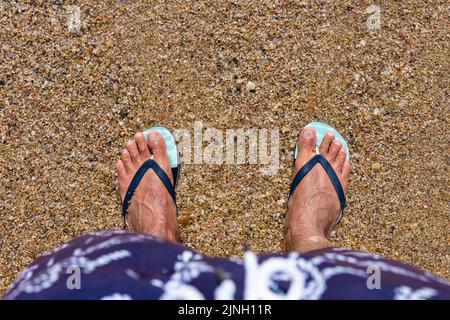 Mans piedi in infradito in spiaggia. Vista dall'alto. Giacitura piatta. Copia spazio, Aggiungi testo Foto Stock