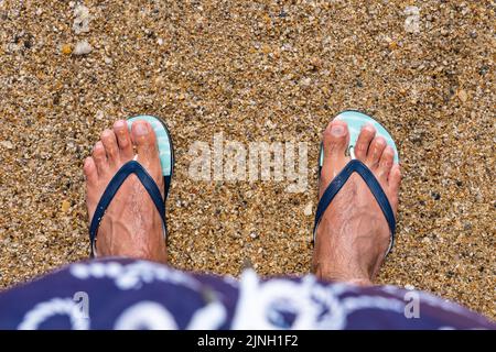 Mans piedi in infradito in spiaggia. Vista dall'alto. Giacitura piatta. Copia spazio, Aggiungi testo Foto Stock