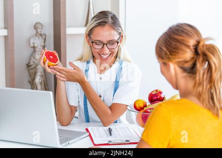 Medico nutrizionista, dietista e paziente di sesso femminile su consultazione in ufficio. Nutrizionista femminile che dà la consultazione al paziente. Fare il programma di dieta. Foto Stock