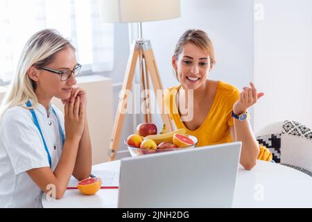 Medico nutrizionista, dietista e paziente di sesso femminile su consultazione in ufficio. Giovane nutrizionista sorridente nella sala di consultazione. Foto Stock