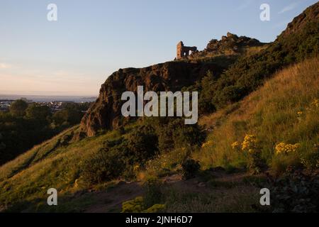 Il tramonto si affaccia sulle rovine della Cappella di St Anthony nell'Holyrood Park di Edimburgo Foto Stock