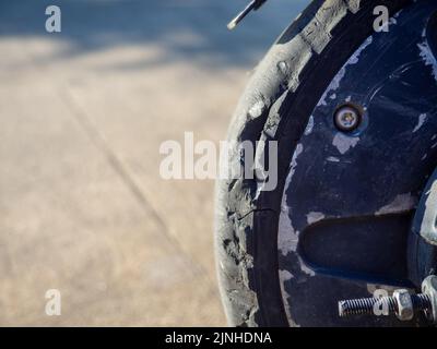 Parte di un primo piano di uno scooter elettrico. Pneumatico rotto. Ruota dello scooter rotta. Attrezzo di propulsione. Veicoli per il divertimento Foto Stock