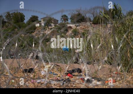 Eagle Pass, Texas, Stati Uniti. 11th ago, 2022. L'abbigliamento migrante è visto attraverso filo spinato vicino al Rio Grande River in Eagle Pass, Texas, Giovedi 11 agosto 2022. (Credit Image: © Allison Dinner/ZUMA Press Wire) Foto Stock