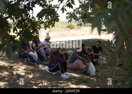 Eagle Pass, Texas, Stati Uniti. 11th ago, 2022. Un gruppo di migranti attende di essere processato dalla polizia di frontiera degli Stati Uniti dopo aver attraversato illegalmente il fiume Rio Grande dal Messico verso proprietà privata a Eagle Pass, Texas, giovedì 11 agosto 2022. (Credit Image: © Allison Dinner/ZUMA Press Wire) Foto Stock