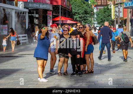 Cattura l'emozione e l'energia di Las Vegas con questa immagine di un gruppo di turisti che si fermano per scattare foto di se stessi al LINQ Promenade. Il Foto Stock