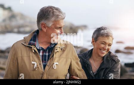 Proprio come i bei vecchi tempi: Una bella coppia anziana che fa una passeggiata in spiaggia. Foto Stock