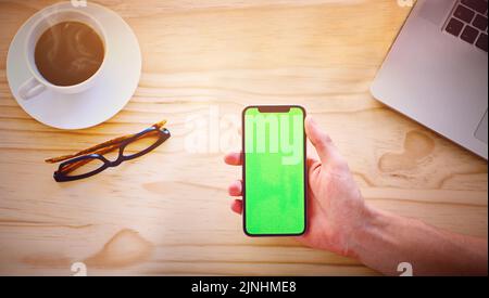 Notizie del mondo nel palmo della tua mano. Scatto ad angolo alto di un uomo irriconoscibile che tiene in mano uno smartphone che visualizza il tasto chroma sullo schermo di un ufficio Foto Stock