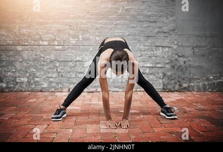 Sciogliendo e svegliando tutto il corpo, una giovane donna sportiva che si esercita all'aperto. Foto Stock